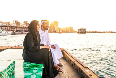 Arabian married couple visiting Dubai on abra boat - Two people on traditional boat at Dubai creek - DMDF01028