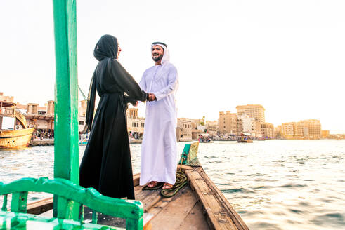 Arabian married couple visiting Dubai on abra boat - Two people on traditional boat at Dubai creek - DMDF01029