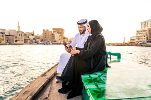 Arabian married couple visiting Dubai on abra boat - Two people on traditional boat at Dubai creek - DMDF01031