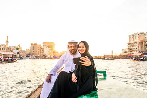 Arabian married couple visiting Dubai on abra boat - Two people on traditional boat at Dubai creek - DMDF01034