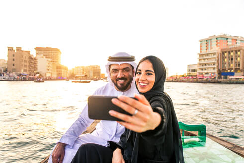 Arabian married couple visiting Dubai on abra boat - Two people on traditional boat at Dubai creek - DMDF01035