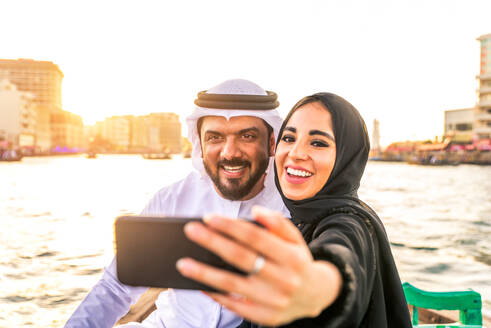 Arabian married couple visiting Dubai on abra boat - Two people on traditional boat at Dubai creek - DMDF01036