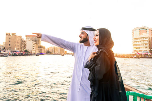 Arabian married couple visiting Dubai on abra boat - Two people on traditional boat at Dubai creek - DMDF01037