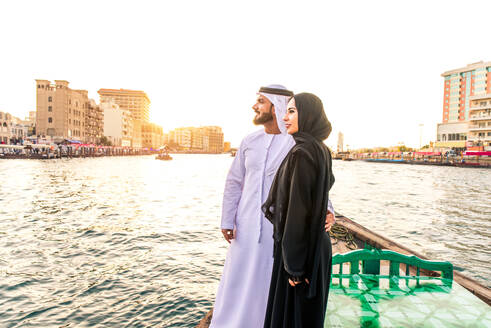 Arabian married couple visiting Dubai on abra boat - Two people on traditional boat at Dubai creek - DMDF01038