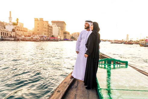 Arabian married couple visiting Dubai on abra boat - Two people on traditional boat at Dubai creek - DMDF01039