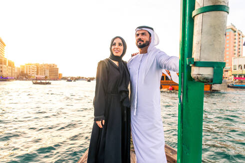 Arabian married couple visiting Dubai on abra boat - Two people on traditional boat at Dubai creek - DMDF01040