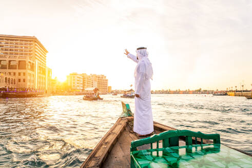 Arabian man wearing kandura on abra boat on Creek's canal in Dubai - DMDF01042