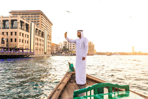 Arabian man wearing kandura on abra boat on Creek's canal in Dubai - DMDF01043