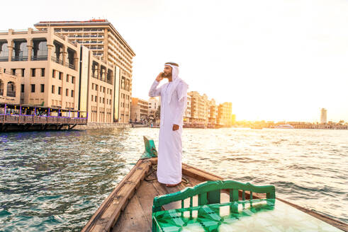 Arabian man wearing kandura on abra boat on Creek's canal in Dubai - DMDF01044