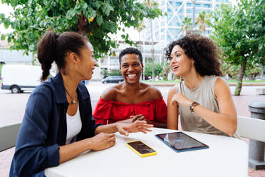 Happy beautiful hispanic south american and black women meeting outdoors and having fun - Black adult females friends spending time together sitting in a bar cafè - DMDF01059