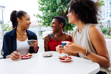Happy beautiful hispanic south american and black women meeting outdoors and having fun - Black adult females friends spending time together sitting in a bar cafè - DMDF01065
