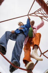 Couple standing on rope equipment in park - AFVF09300