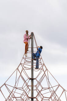 Couple climbing on jungle gym in park - AFVF09304