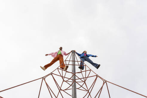 Verspieltes Paar verbringt seine Freizeit auf dem Klettergerüst im Park - AFVF09309