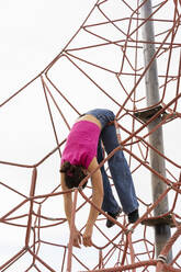 Playful woman hanging on rope equipment under sky - AFVF09313