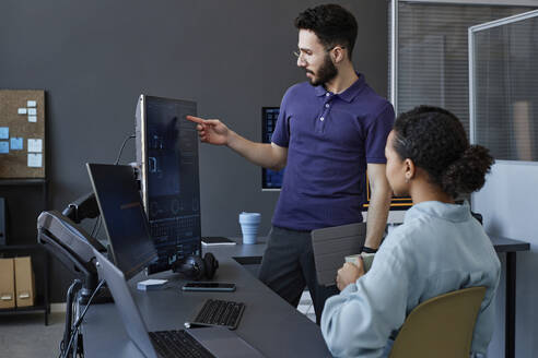 Computerprogrammierer bei einer Diskussion über einen Desktop-PC im Büro - KPEF00070