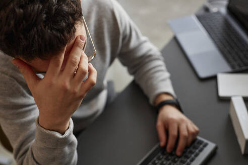 Stressed IT professional sitting at desk - KPEF00096