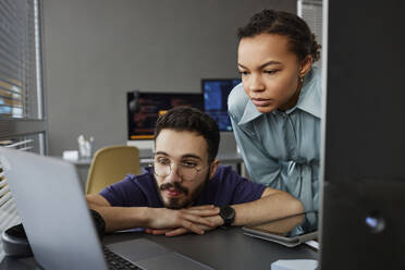 IT-Fachleute arbeiten gemeinsam an einem Laptop am Schreibtisch - KPEF00109