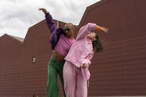 Glückliche Freunde tanzen zusammen vor einem Gebäude - AFVF09378