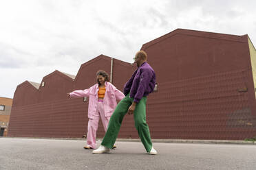 Woman dancing with friend in front of building - AFVF09380