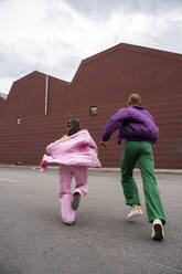 Friends running together in front of building - AFVF09386