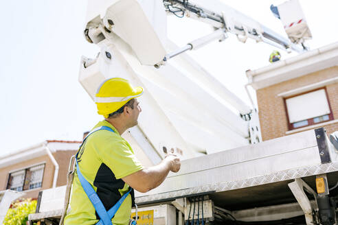 Engineer showing thumbs up gesture standing in front of hydraulic platform - JJF01085