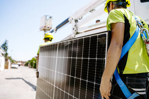 Engineers carrying solar panels on sunny day - JJF01089