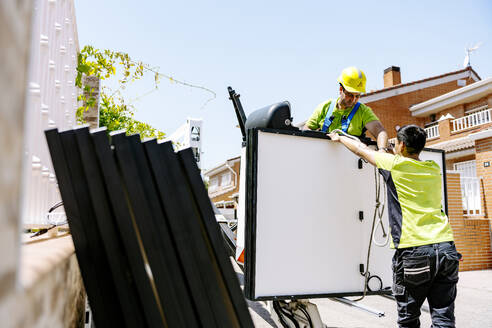 Engineers working with solar panels on sunny day at site - JJF01106