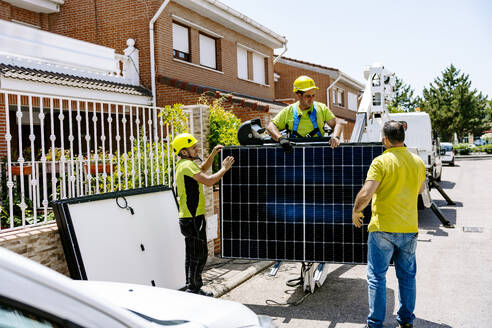 Engineers holding solar panel and standing on road - JJF01112