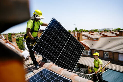 Ein Solaringenieur installiert Solarmodule auf einem Dach, um die Energie der Sonne für eine nachhaltige Stromversorgung zu nutzen - JJF01115