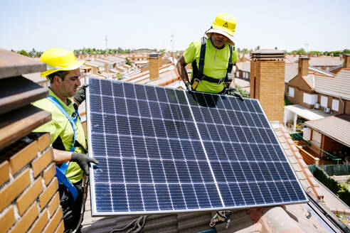 Ein Solaringenieur installiert Solarmodule auf einem Dach, um die Energie der Sonne für eine nachhaltige Stromversorgung zu nutzen - JJF01117