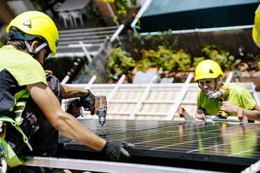 Ein Solaringenieur installiert Sonnenkollektoren in einem Wohngebiet, um erneuerbare Energie zu gewinnen - JJF01120