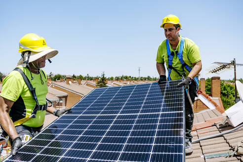 Erfahrener Solaringenieur bei der Installation nachhaltiger Sonnenkollektoren in einem Wohngebiet zur Förderung der Nutzung erneuerbarer Energien - JJF01122