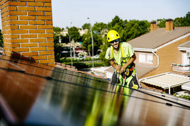 Ein Solaringenieur installiert Paneele in einem Wohngebiet, um erneuerbare Energie aus der Sonne zu gewinnen - JJF01132