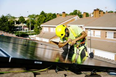 Ein Solaringenieur installiert Solarzellen auf einem Dach, um nachhaltige Energie aus der Sonne zu gewinnen - JJF01133