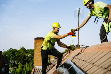 Ein Solaringenieur installiert Solarzellen in einem Wohngebiet, um erneuerbare Energien zur Stromversorgung von Häusern zu nutzen - JJF01137