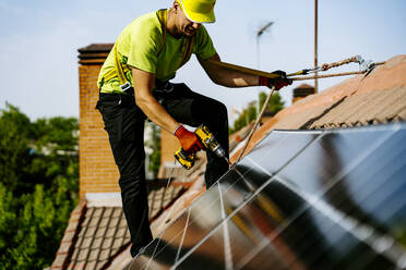 Ein Solaringenieur installiert Solarmodule in einem Wohngebiet, um erneuerbare Energien zur Stromversorgung von Häusern und zur Verringerung von Kohlenstoffemissionen zu nutzen - JJF01138