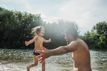 Eine rührende Szene entfaltet sich, als ein kleiner Junge seinen Vater am malerischen Flussufer von Nischni Nowgorod, Russland, glücklich umarmt - ANAF01921