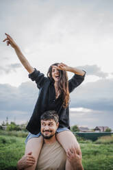 Happy man carrying woman on shoulders in the countryside - ANAF01923