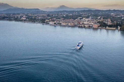 Italy, Veneto, Lazise, Aerial view of ferry arriving at lakeshore town - AMF09950