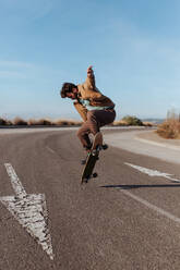 Ein geübter Skater vollführt mühelos einen Kickflip, während er mit seinem Skateboard über den glatten Asphalt gleitet - ADSF46446