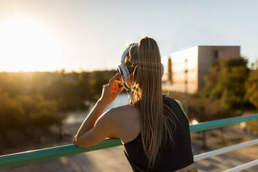 Young athletic caucasian leaning on banister stretching outdoors near road - ADSF46486