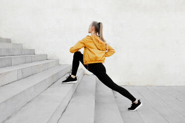 Young athletic caucasian woman stretching out outdoors near stairs - ADSF46497