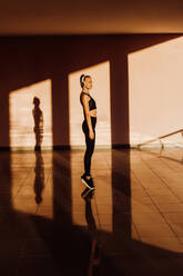 Young athletic caucasian woman working out at sunset, shadows and light on background - ADSF46501