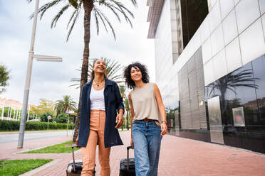 Happy beautiful hispanic south american women meeting outdoors and having fun - Black adult females friends spending time together on a touristic travel - DMDF01185