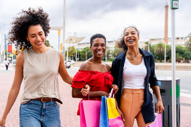 Glückliche schöne hispanische südamerikanische und schwarze Frauen, die sich im Freien treffen und Spaß haben - Schwarze erwachsene Freundinnen, die Zeit miteinander verbringen und in der Stadt zum Einkaufen gehen - DMDF01192