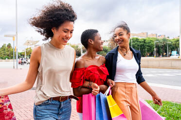 Glückliche schöne hispanische südamerikanische und schwarze Frauen, die sich im Freien treffen und Spaß haben - Schwarze erwachsene Freundinnen, die Zeit miteinander verbringen und in der Stadt zum Einkaufen gehen - DMDF01193