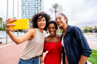 Happy beautiful hispanic south american and black women meeting outdoors and having fun - Black adult females friends spending time together and walking in the city for shopping - DMDF01195