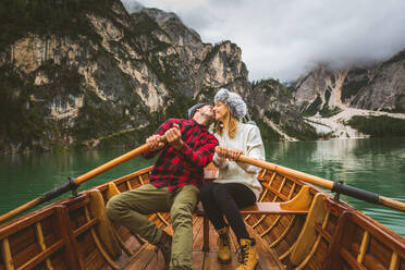 Beautiful couple of young adults visiting an alpine lake at Braies, Italy - Tourists with hiking outfit having fun on vacation during autumn foliage - Concepts about travel, lifestyle and wanderlust - DMDF01211