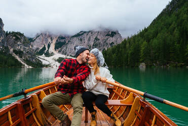 Beautiful couple of young adults visiting an alpine lake at Braies, Italy - Tourists with hiking outfit having fun on vacation during autumn foliage - Concepts about travel, lifestyle and wanderlust - DMDF01214